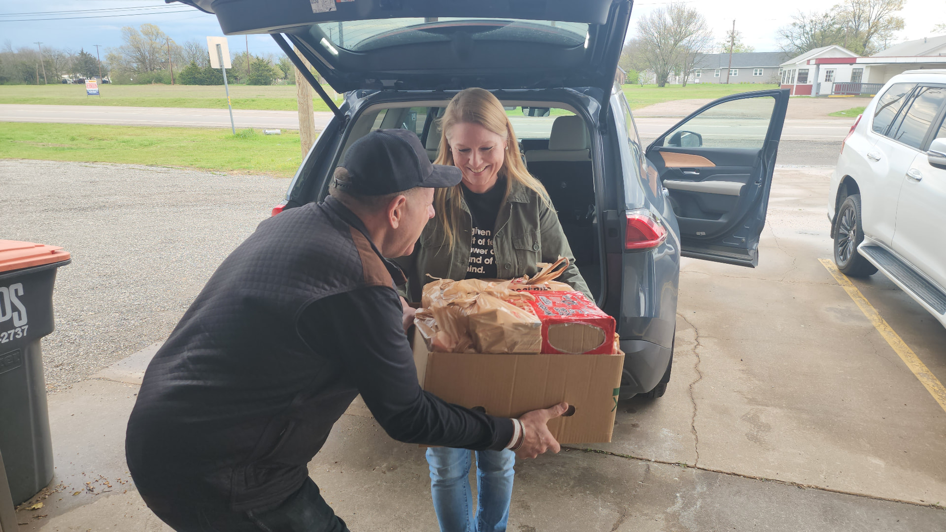 Leon Shasteen loading a box of groceries into a family's car at Grace Place